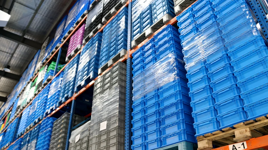 Tall warehouse racks filled with neatly stacked blue and grey plastic containers